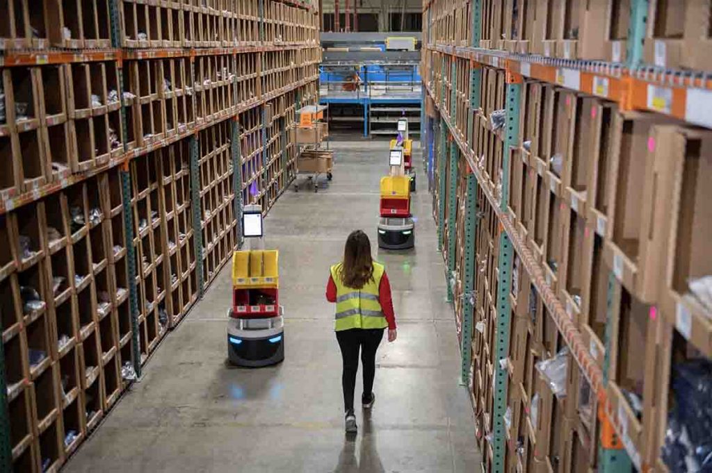 Woman Walking Next to Locus Logistics Robots in Facility